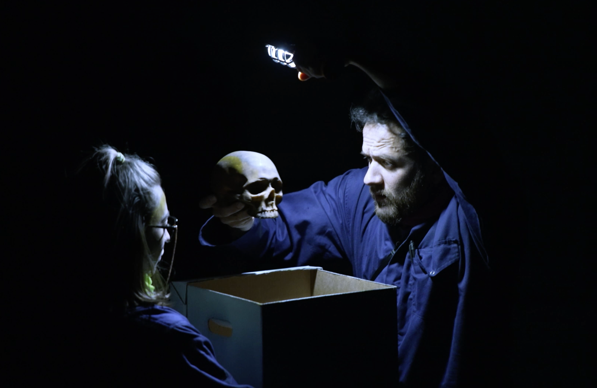 Two people study a skull which is being lifted out of a box